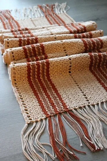 A striped table runner with tassels is folded to show the pattern