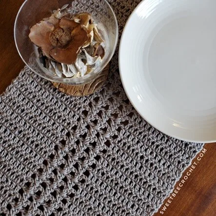 A table runner crocheted in solid and openwork has bowls resting on it