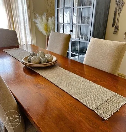 A table runner with a fringe decorates a dining table 