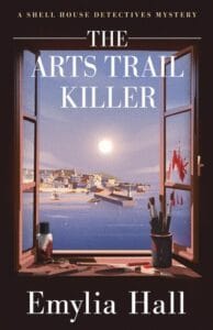 Book cover for The Arts Trail Killer by Emylia Hall, part of “A Shell House Detectives Mystery” series. The artwork shows an open window overlooking a seaside village under a full moon, with calm blue water and boats in the harbor. Inside the window frame are art supplies and paintbrushes, with red paint smeared ominously on the right window pane, suggesting a crime scene.