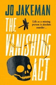 Book cover for "The Vanishing Act" by Jo Jakeman. The design features bold yellow and white text on an orange background. A black skull sits at the bottom, with a dragonfly above the title. The tagline reads, “Life as a missing person is absolute murder…”