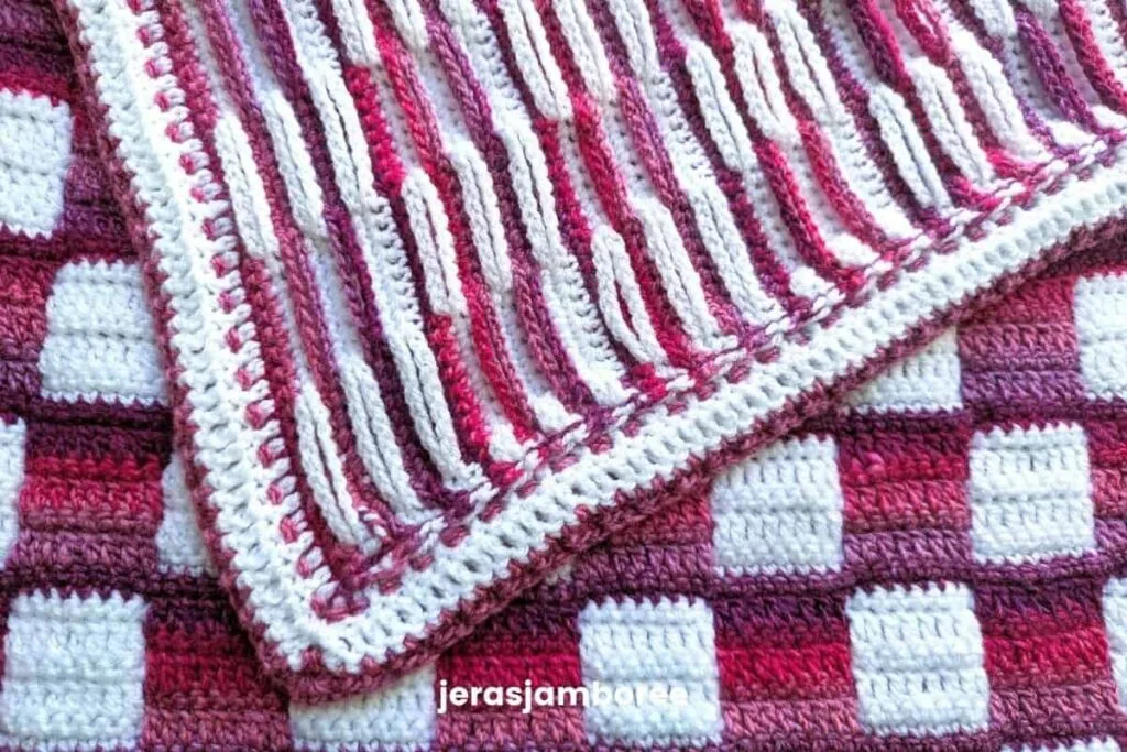 Close-up of the Mindful Hands Mosaic Blanket showing the inset mosaic chains on the back, with the pink and white gingham pattern visible on the front and the textured border edge.
