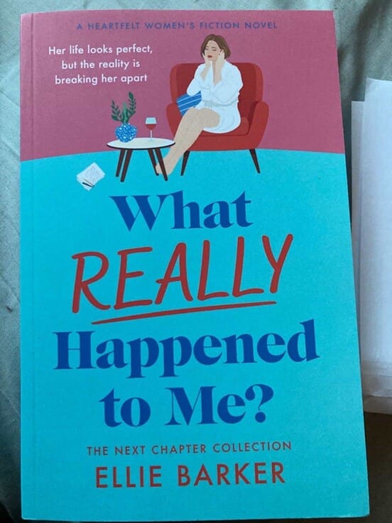 Book cover of What Really Happened to Me by Ellie Barker. The illustrated cover shows a woman sitting thoughtfully in an armchair with a glass of wine, against a pink and turquoise background, with the subtitle “Her life looks perfect, but the reality is breaking her apart.”