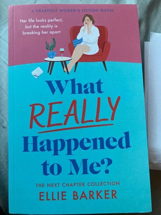 Book cover of What Really Happened to Me by Ellie Barker. The illustrated cover shows a woman sitting thoughtfully in an armchair with a glass of wine, against a pink and turquoise background, with the subtitle “Her life looks perfect, but the reality is breaking her apart.”