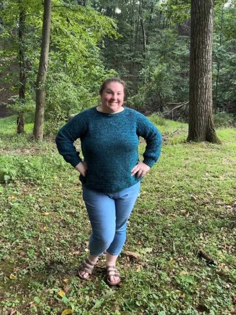 Jess from Craic Creations wearing the Coastal Breeze crochet sweater in a woodland