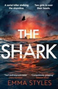 Book cover for The Shark by Emma Styles featuring a dramatic ocean sunset with waves in the foreground, seabirds flying overhead, and a lifeguard tower on the beach beneath a glowing sky.