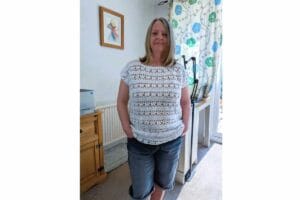 Woman wearing a white crochet summer top with lace stitch detail, styled casually with denim shorts for an easy everyday outfit.
