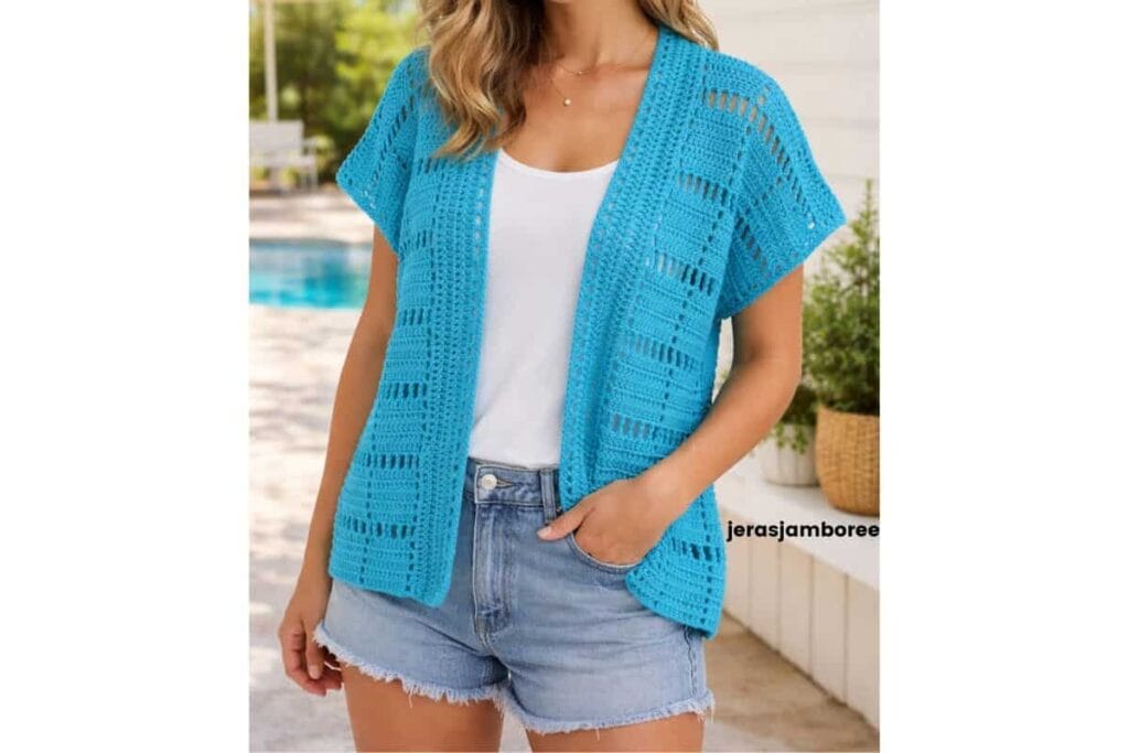 Woman wearing the turquoise Marlowe short sleeve crochet cardigan over a white top and denim shorts in a bright outdoor summer setting.