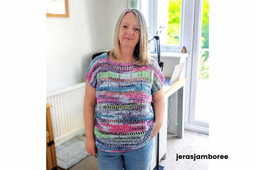 Woman wearing the Marlowe Summer Top crochet pattern in a colourful self-striping cotton yarn. The lightweight filet crochet top has a relaxed fit, cap sleeves, and an airy geometric stitch design for summer layering.