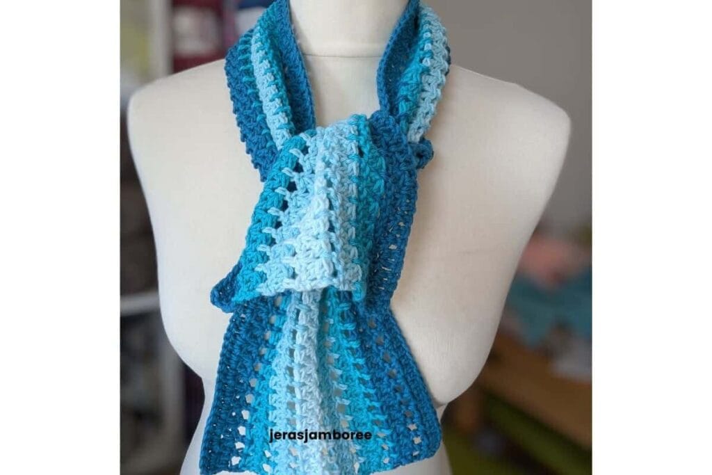 The Sandrine Scarf looped around a mannequin, showing the lightweight mesh stitch and blue striped colour changes.