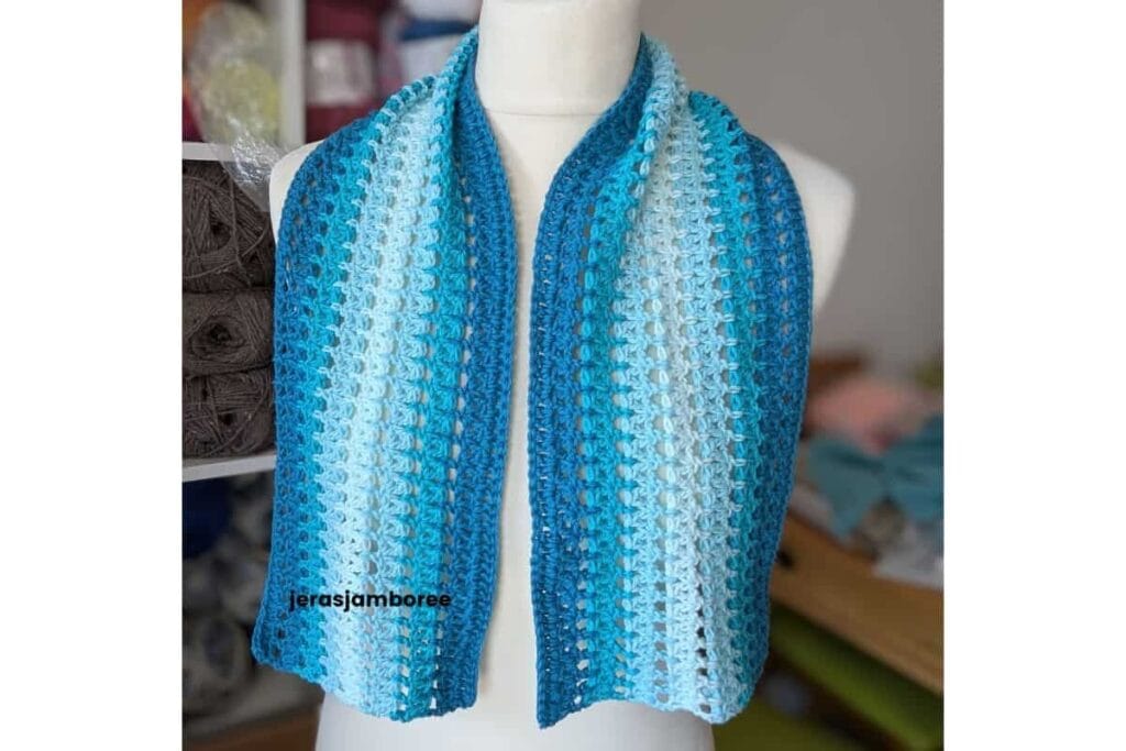 Blue and white striped Sandrine Scarf draped around a mannequin, showing the lightweight fabric and airy double crochet 2 together mesh stitch