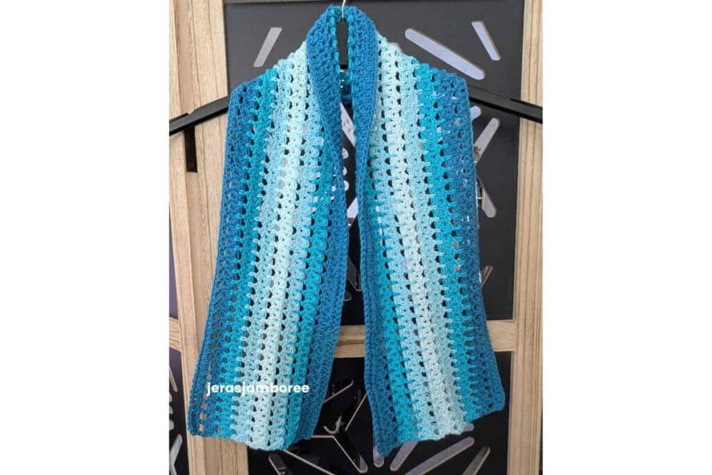 Sandrine Scarf, a free lacy crochet scarf pattern worked in blue and white stripes using an airy double crochet 2 together mesh stitch.