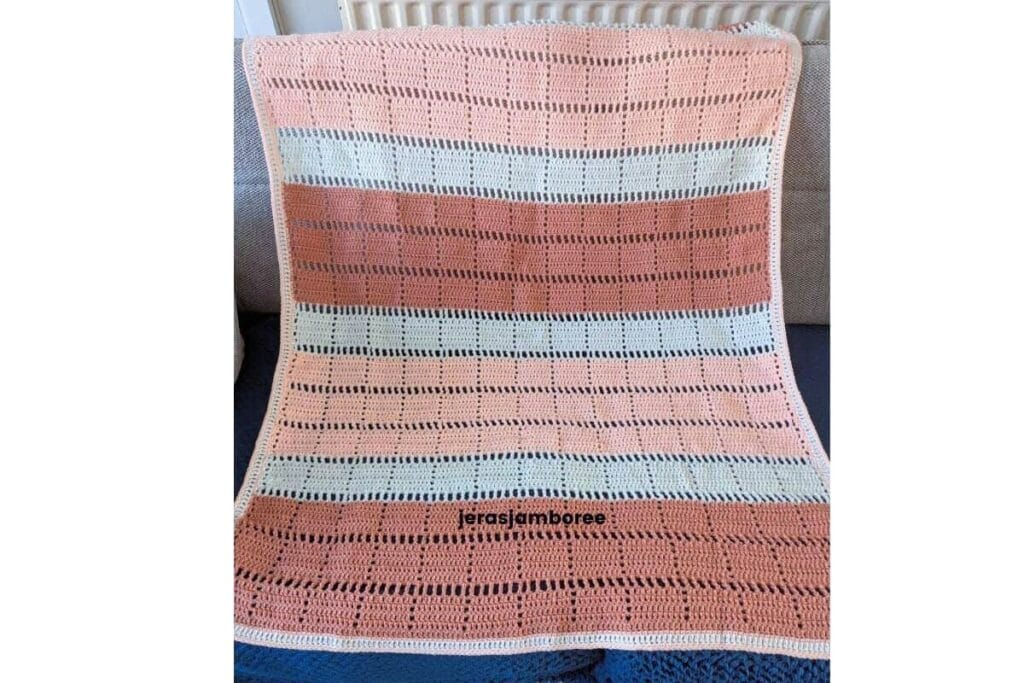 Marlowe crochet lapghan showing the full geometric filet pattern in peach, off white and dusky peach, finished with a simple three-round border